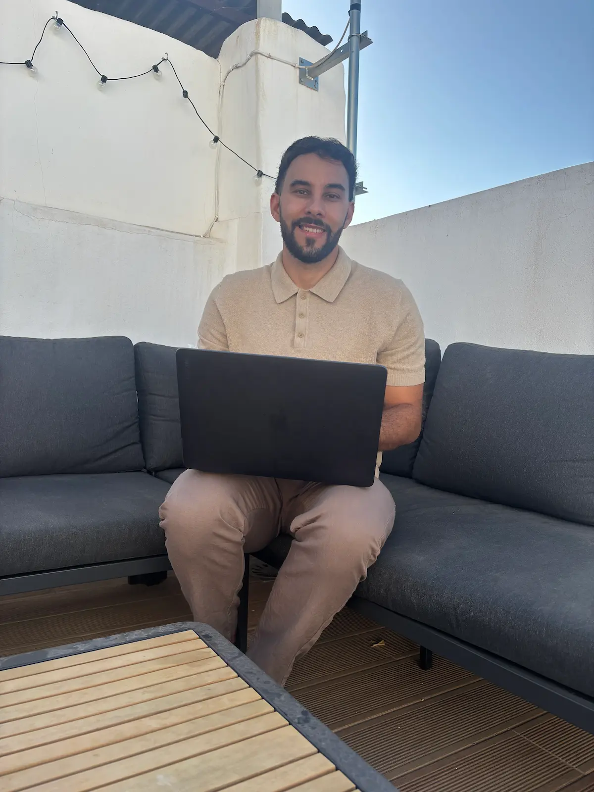 Chris Blassiaux souriant, en terrasse avec son ordinateur portable